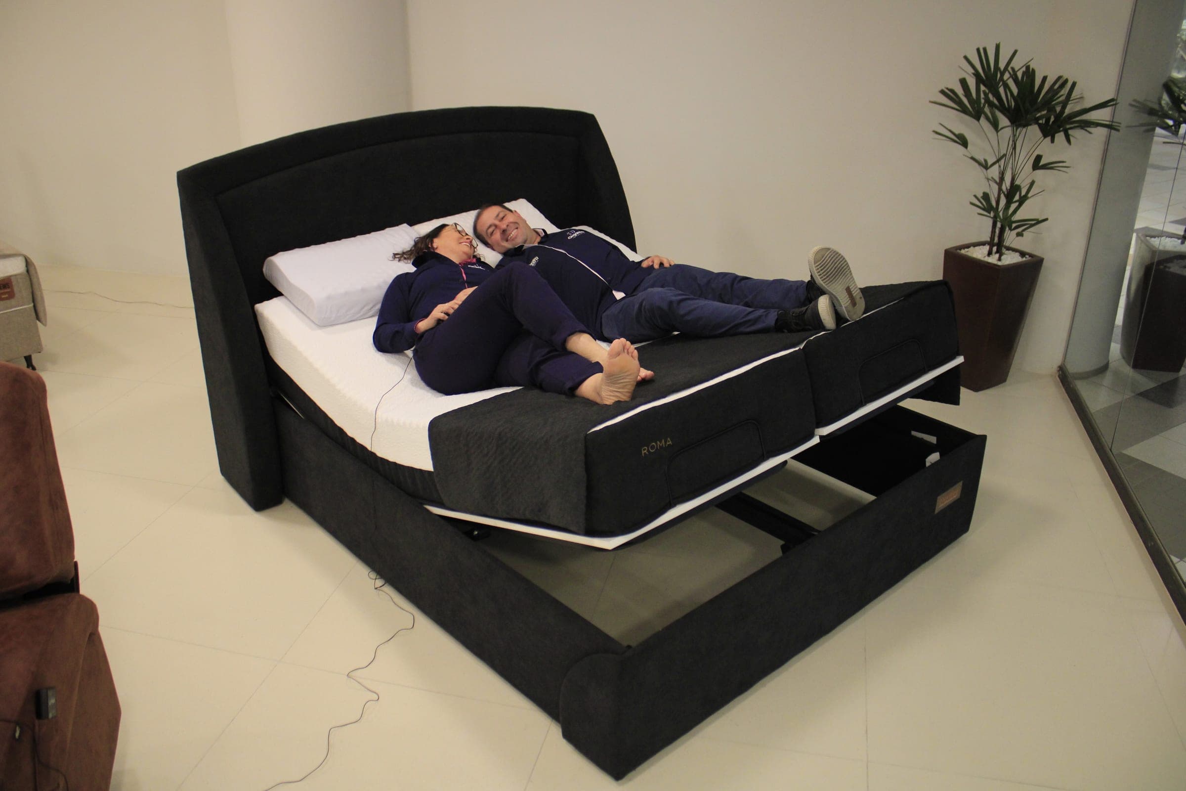 Silvana e Carlinhos deitados em uma cama articulada FlexiBed no showroom