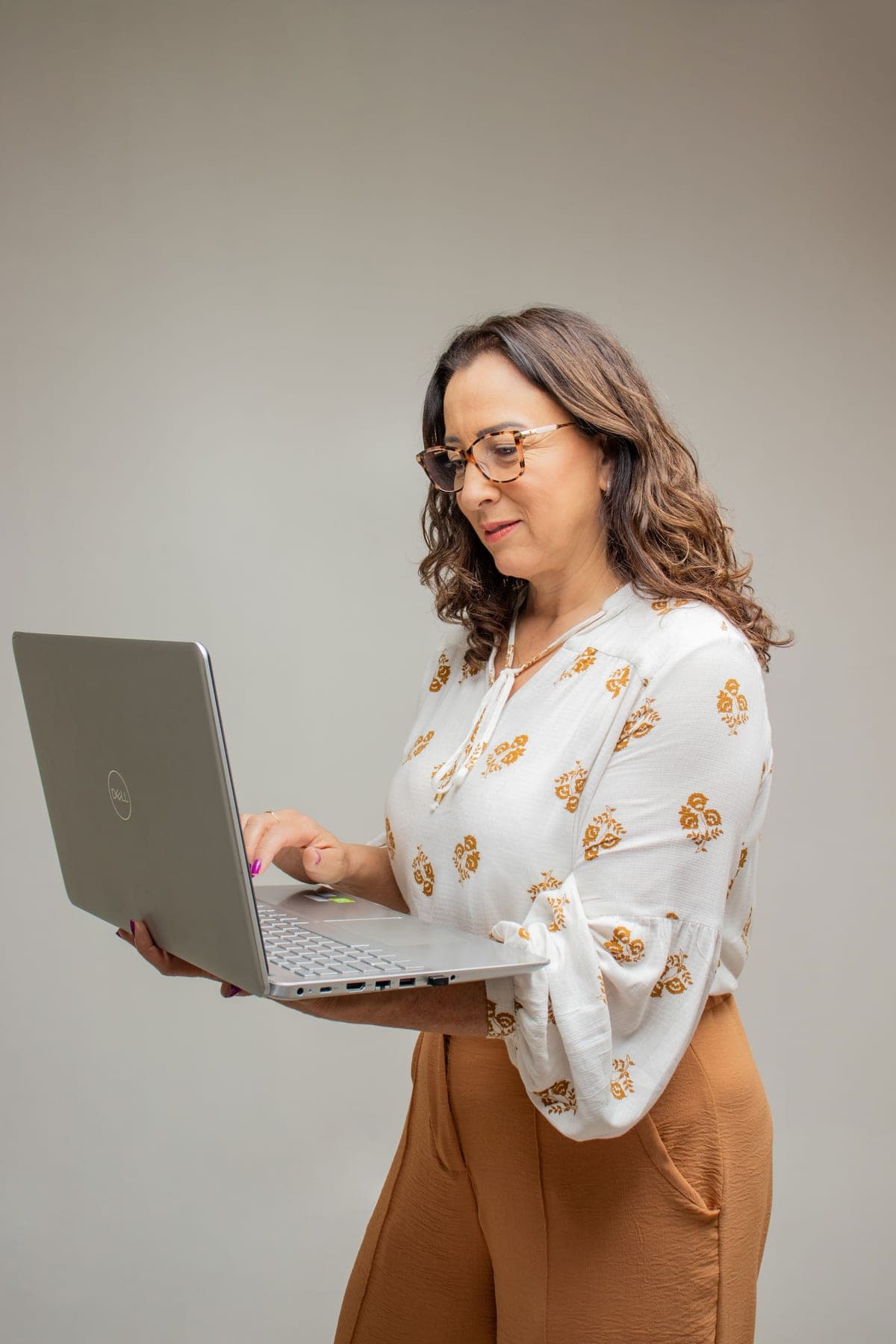 Silvana em pé segurando um notebook, sorrindo